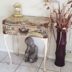 a small statue sitting next to a table with a trunk on it's side