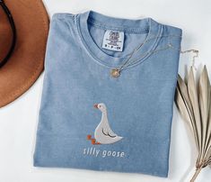 ✨Unisex comfort color shirts✨ These vintage style Comfort Colors shirts capture the essence of retro style with their relaxed fit and timeless appeal. Its adorable "silly goose" design with an embroidered goose adds a cute and fun touch to your wardrobe, making it perfect for going out with friends, weekend adventures, or just lounging in comfort. Made with 100% cotton, they offer a very soft and comfortable feeling from the first moment. Pigment dyed finish gives a vintage, lived in look, plus Goose Design, Friends Weekend, Weekend Adventures, Silly Goose, Shirt Embroidery, Oversized Style, Comfort Color, Embroidered Tshirt, Funny Shirt