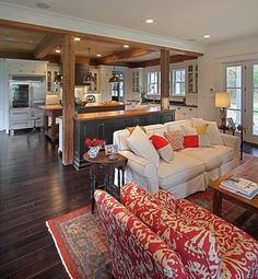 a living room filled with furniture next to a kitchen and dining room table in front of an island