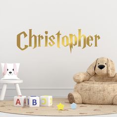 a teddy bear sitting on top of a chair next to a wall with gold lettering