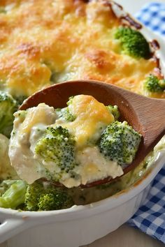 broccoli and cheese casserole in a white dish with a wooden spoon