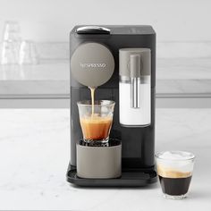 an espresso machine is being filled with coffee and ice cold drinks on a marble countertop