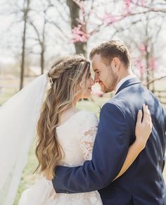 a bride and groom embracing each other in front of cherry blossom trees