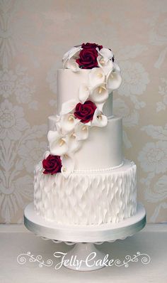 a white and red wedding cake with flowers on top