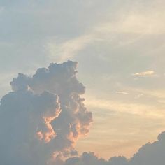 an airplane is flying in the sky with clouds above it and another plane on the ground