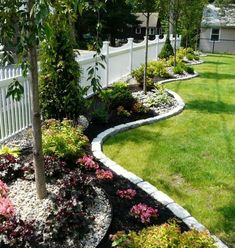 a white fenced in yard with flowers and trees