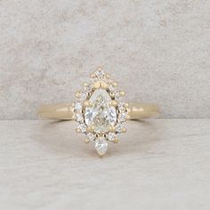 a yellow gold engagement ring with an oval cut diamond surrounded by smaller round brilliant diamonds