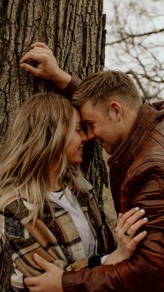 a man and woman hugging in front of a tree