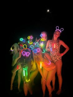 two women in bathing suits with neon glasses and bunny ears on their heads, standing next to each other