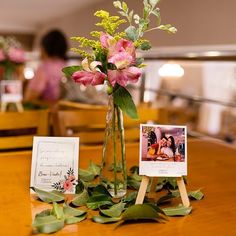 there is a vase with flowers in it and two pictures on the table next to it