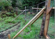 a wooden fence in the middle of a field with grass and trees around it,