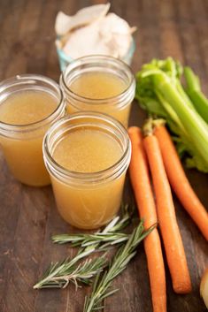 carrots, celery and other vegetables are on a table next to jars