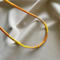 an orange and yellow beaded necklace on a white cloth