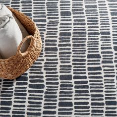 a pair of shoes sitting on top of a rug next to a basket filled with pillows