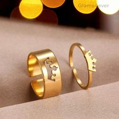 two gold rings with crowns on them sitting next to each other