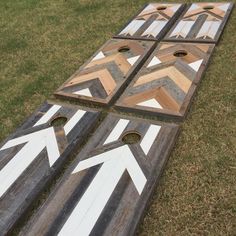 three boards with arrows painted on them sitting in the grass next to each other,