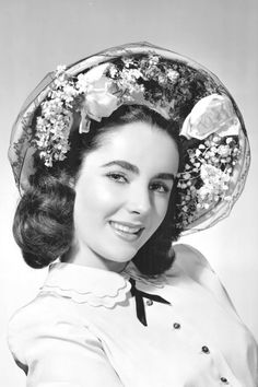 an old photo of a woman wearing a hat with flowers on it