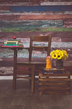 a wooden table topped with a vase filled with yellow flowers next to a brown chair