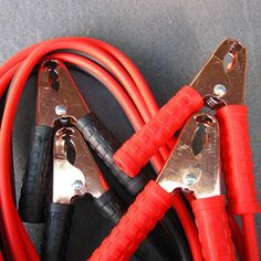 two red and black wires connected to each other on top of a gray surface with metal clips