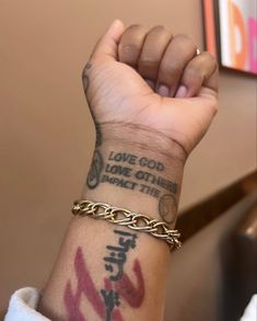 a person with a tattoo on their arm holding up a gold chain bracelet that says love god some other than the cross