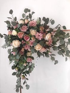 a bunch of flowers that are on top of a wooden stand in front of a wall