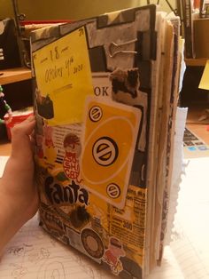 a person is holding up a book covered in stickers and other things that are on top of it