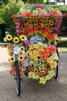 a bicycle decorated with flowers and an umbrella on the back is parked in front of a brick walkway