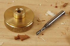 a metal object sitting on top of a wooden table next to a pen and some wood shaving