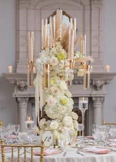 a tall centerpiece with white flowers and gold candles is surrounded by other table settings