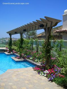 an outdoor swimming pool surrounded by flowers and greenery