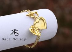 "Heart locket bracelet with engraved monogram. Bracelet will be featured with large link chain and toggle clasp. Add your message, date or inspirational word on the back of the locket for additional cost. Locket opens and holds 2 photos inside. Designs by Keti Sorely. Available Metal - Brass with 24K Yellow Gold Overlay - Brass with 14K Rose Gold Overlay - 14K Yellow Gold Filled - Sterling Silver - Sterling Silver with 14K Rose Gold overlay - Sterling Silver with 24K Yellow Gold overlay Locket i Elegant Heart Bracelet With Toggle Clasp For Gift, Valentine's Day Gift Bracelet With Toggle Clasp, Valentine's Day Heart Bracelet With Toggle Clasp, Valentine's Day Gift Heart Bracelet With Toggle Clasp, Heart Locket Bracelet, Monogram Bracelet, Locket Bracelet, Bracelet In Silver, Gold Overlay