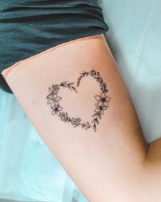 a woman with a tattoo on her arm that has flowers in the shape of a heart