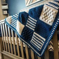 a crocheted blanket hanging from the side of a wooden rail in a room