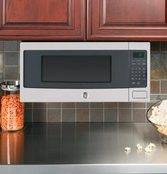 a microwave oven sitting on top of a kitchen counter next to a bowl of popcorn