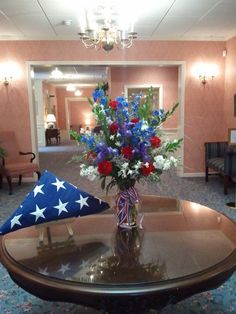 a vase filled with red, white and blue flowers sitting on top of a table