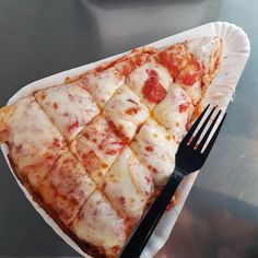 a slice of pizza on a paper plate with a fork