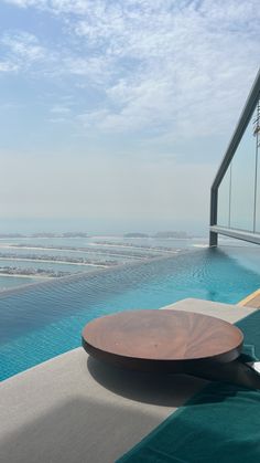 a wooden table sitting on the edge of a swimming pool next to an ocean view