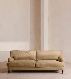 a beige couch sitting on top of a hard wood floor next to a white wall