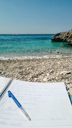 Notebook and blue pen on a pebble beach in Albania on a sunny day. 2025 Goals, Brand Deals, Travel Brand, Attract Money