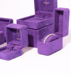 an assortment of purple velvet jewelry boxes with diamond rings and bracelets in them on a white surface