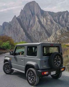 the jeep is parked on the side of the road with mountains in the back ground