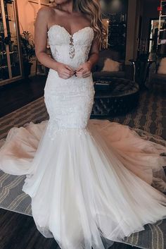 a woman in a wedding dress standing on a bed