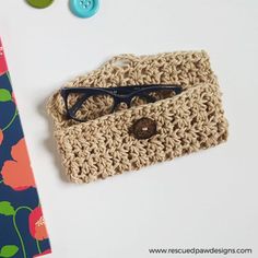 a crocheted pouch with eyeglasses on it next to a flowered notebook