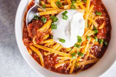 a bowl of chili with cheese and sour cream