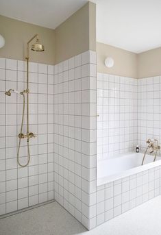 a white tiled bathroom with gold fixtures and bathtub, shower head, and sink faucet