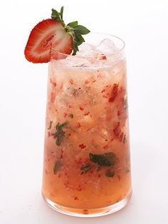 a glass filled with ice and strawberries on top of a table