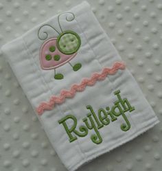 a white towel with a pink and green ladybug embroidered on it