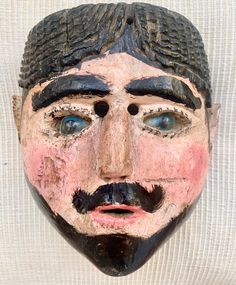 an old mask with black hair and mustaches on it's face is displayed