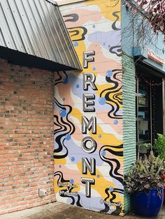 there is a large mural on the side of this building that says fremont street next to some potted plants