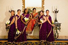 a group of women standing next to each other in front of a mirror on a wall